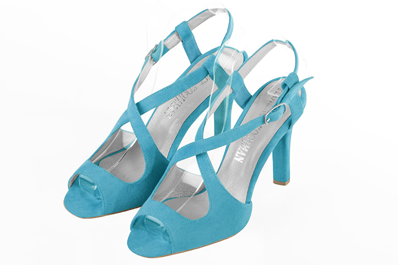 Turquoise blue open back sandals with crossed straps. Round toe